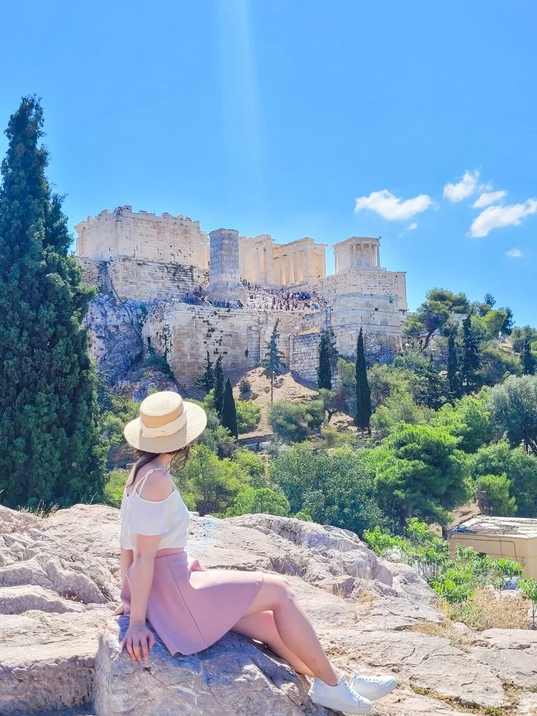 Woman sitting looking at the Acropolis in the distance in Athens, Greece